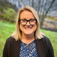 Smiling woman in outdoor setting representing community outreach and support programs.